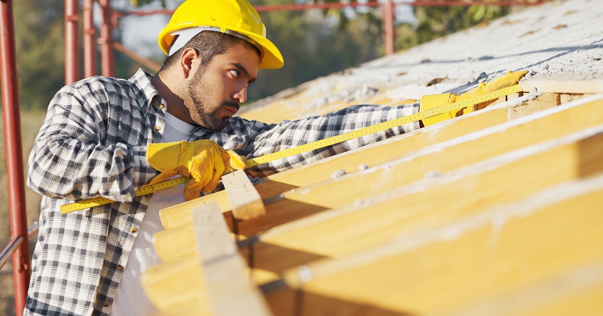 Construction worker uses tape measure