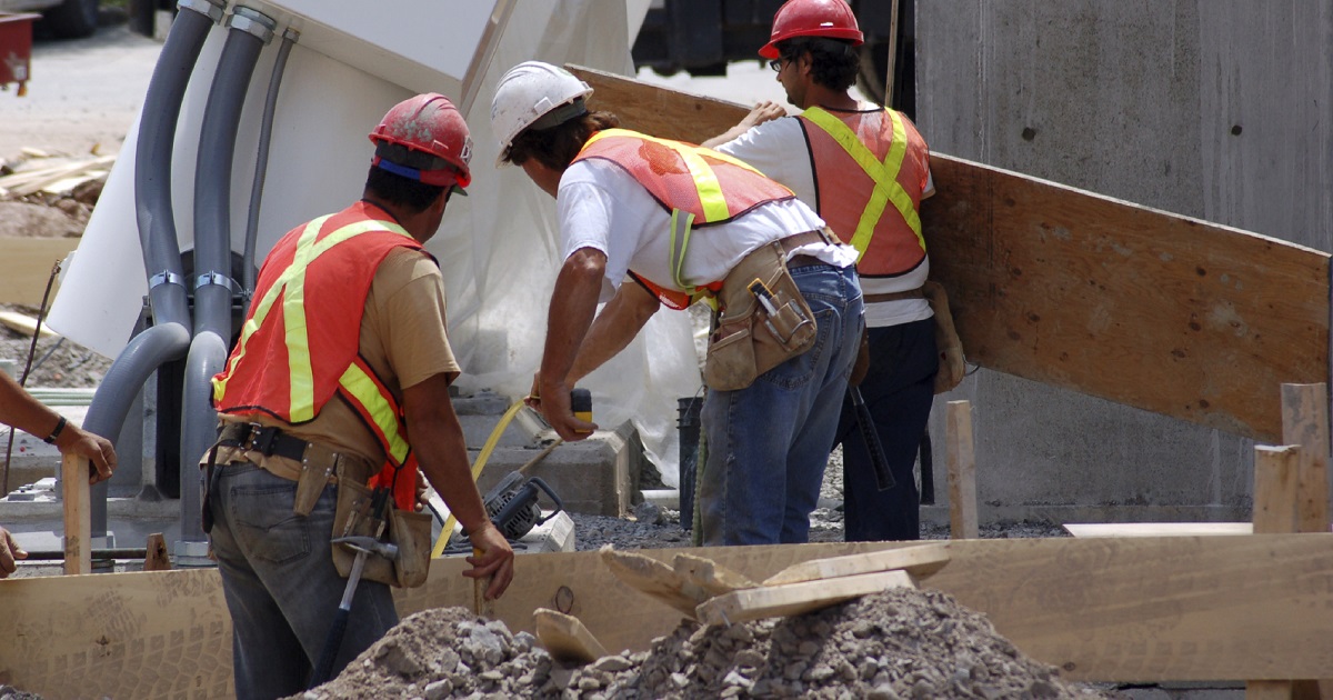 Construction workers wearing PPE work on a job site