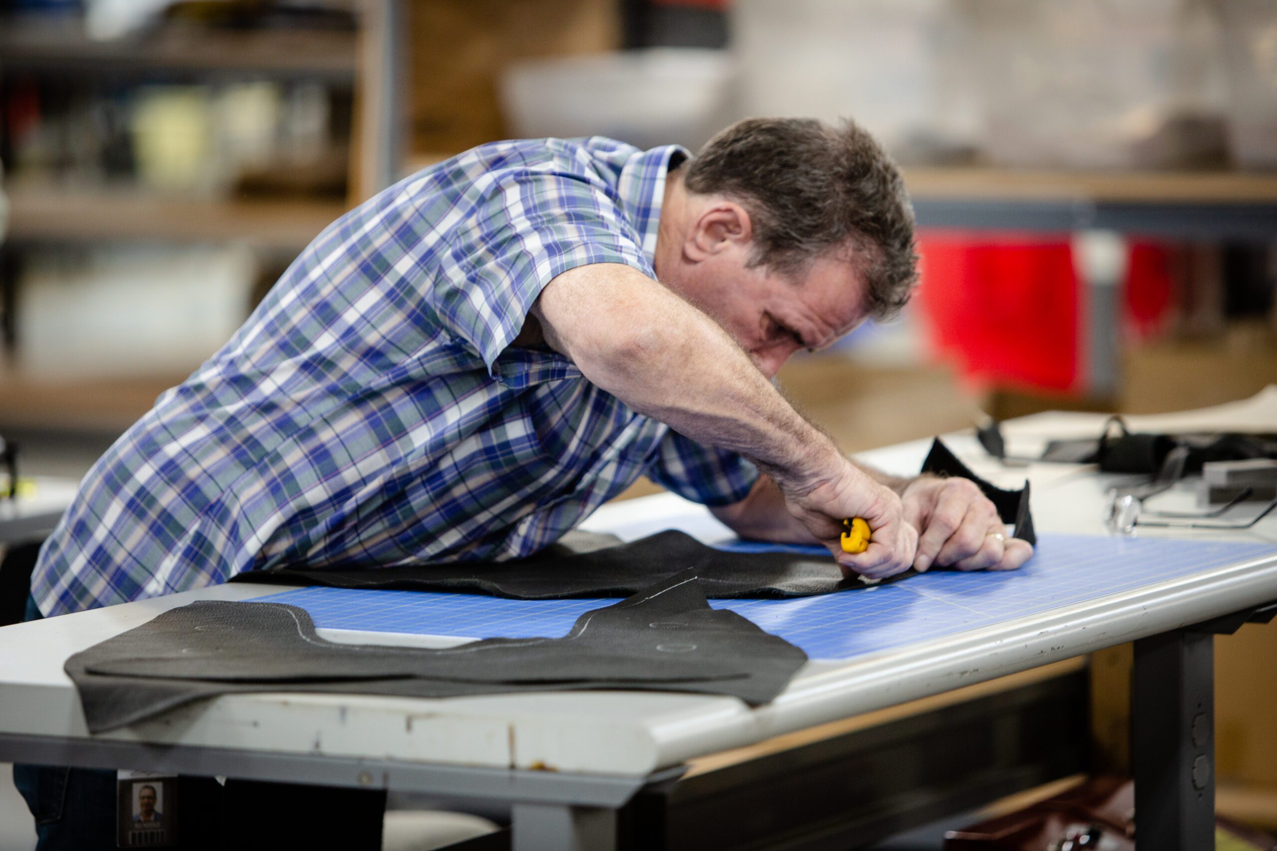 Employee hand cuts leather in manufacturing shop