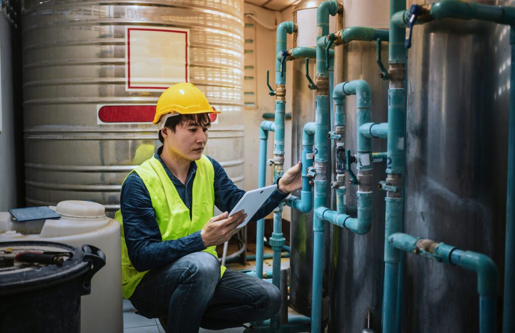 A skilled engineer is seen utilizing a tablet computer to efficiently monitor the Reverse Osmosis system in a drinking water factory.
