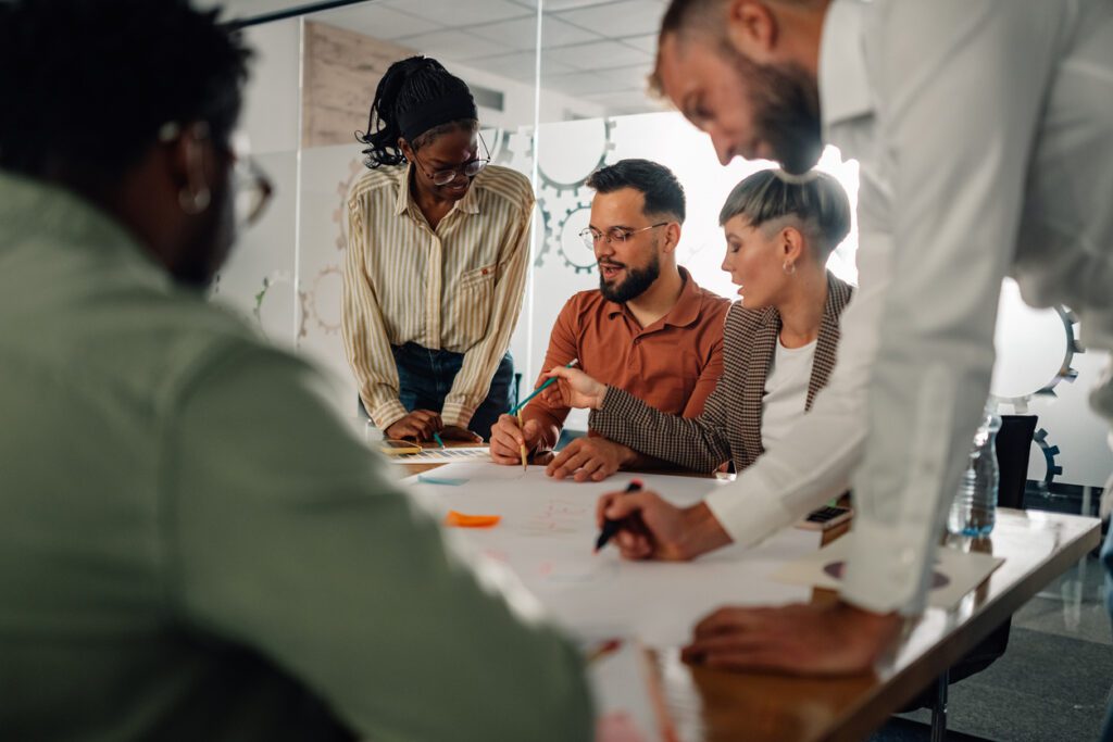 Diverse team of businesspeople collaborating on a project, exchanging ideas and engaging in productive discussions during a dynamic office meeting focused on strategy and innovation