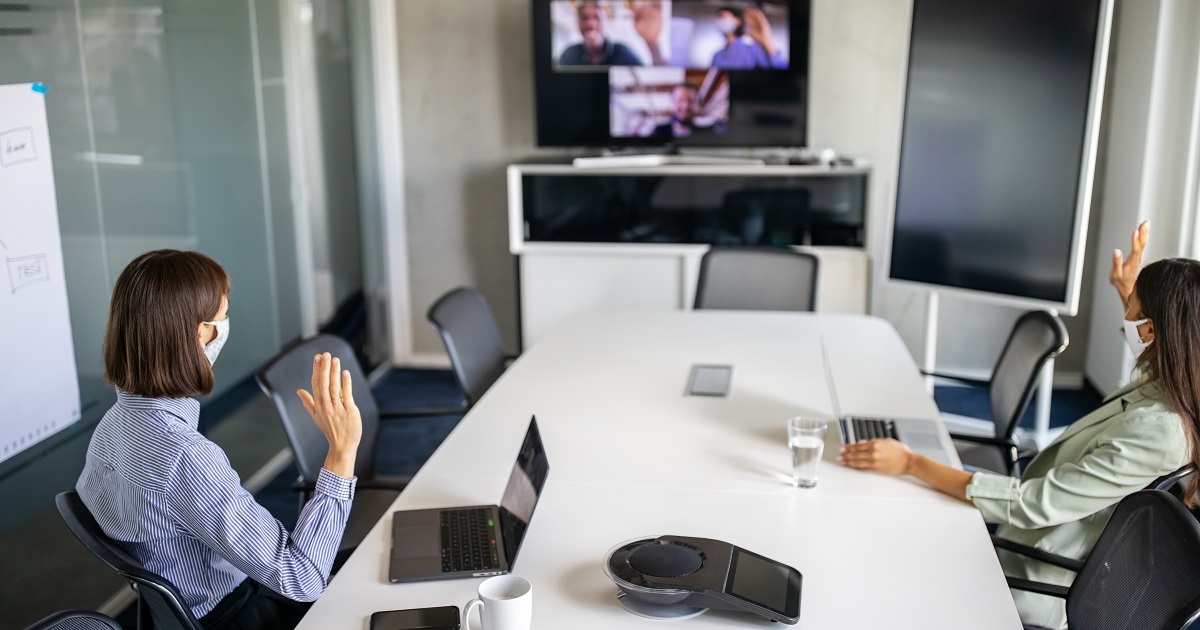 Professionals in an office wear masks while video conferencing