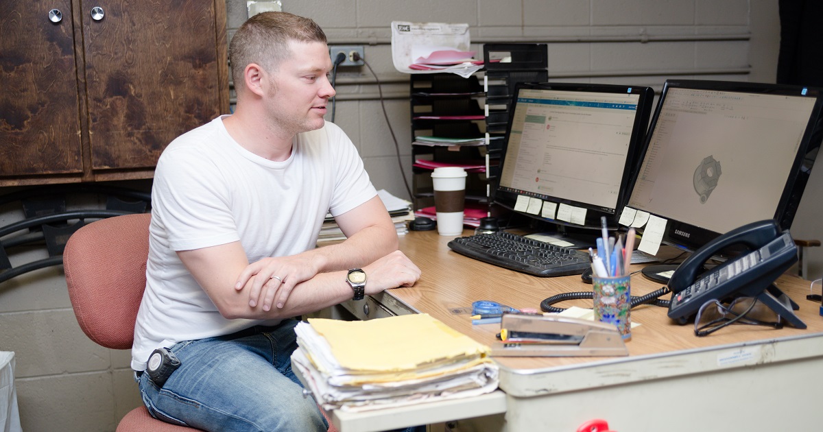 Man sitting at computer with files