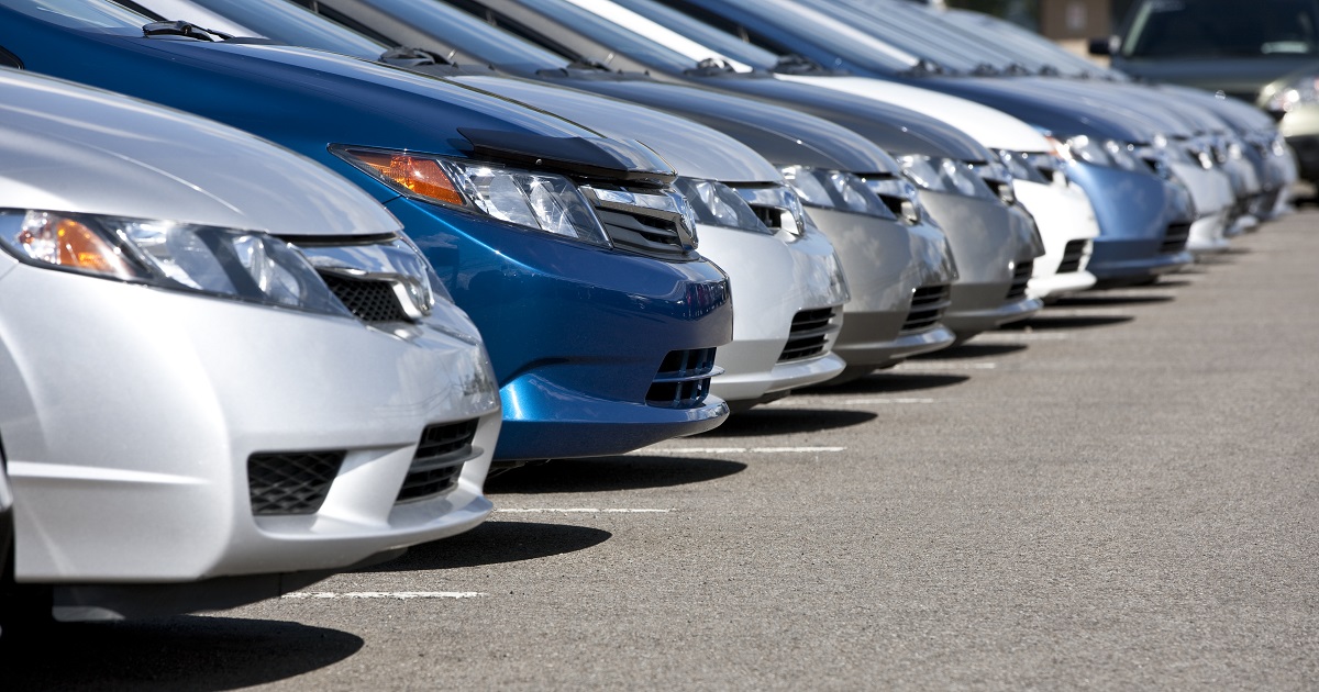 Line of new compact cars at dealership.