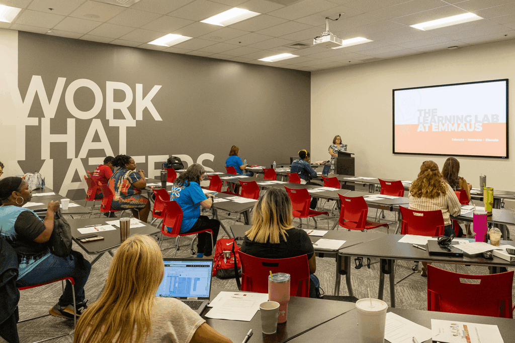 Emmaus team members sit in red chairs in a classroom at The Learning Lab at Emmaus.